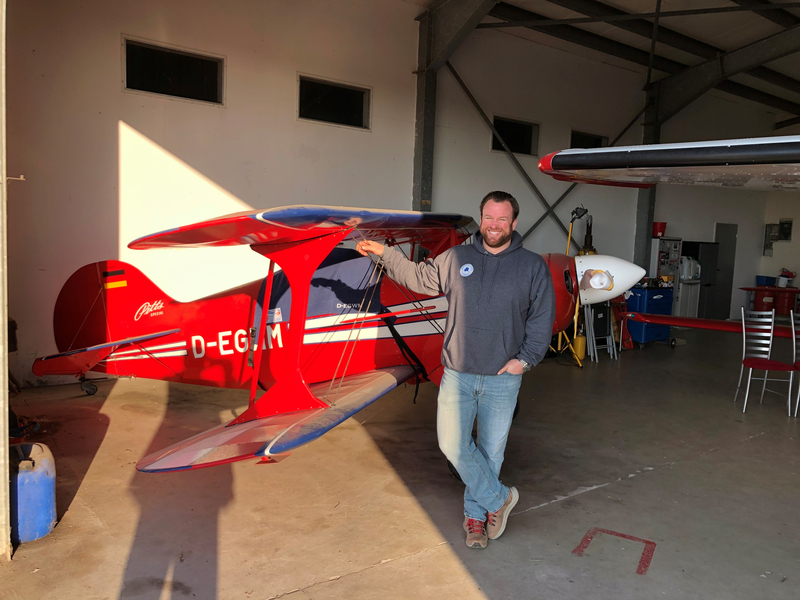 Employee next to his red Pitts in the hangar