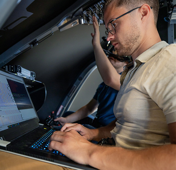 Softwareentwickler prüft mit dem Laptop die Avionik im Simulator-Cockpit