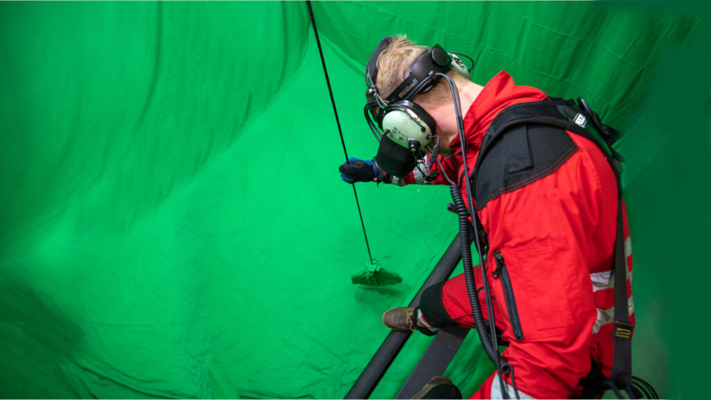 hoistAR operator on the real hoist cable in front of the green screen