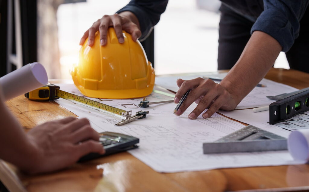 Projektplanung mit technischen Zeichnungen und Schutzhelm