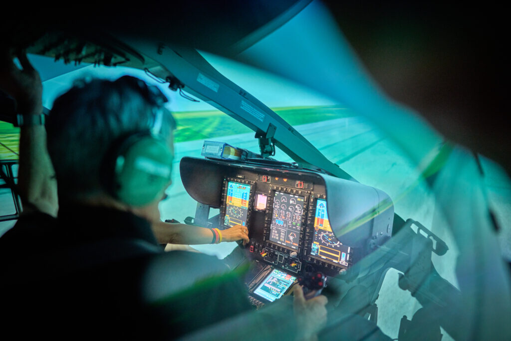 Pilot bedient die Center-Displays im Simulator-Cockpit, in der Projektion die Landebahn
