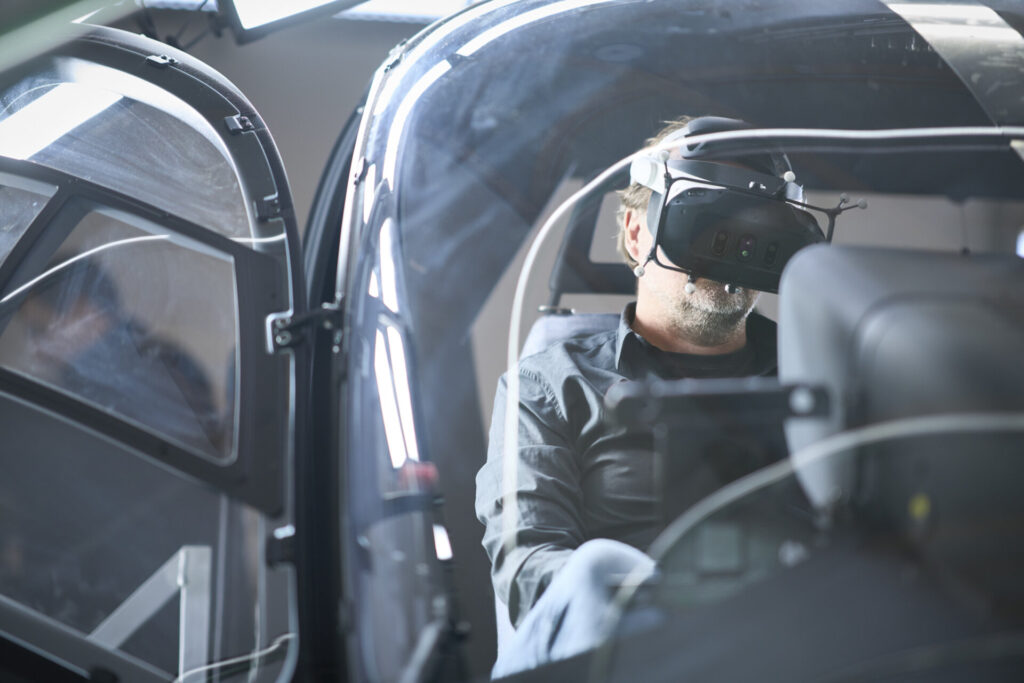 Pilot wearing a mixed reality headset in the full-scale cockpit of the XR-SIM