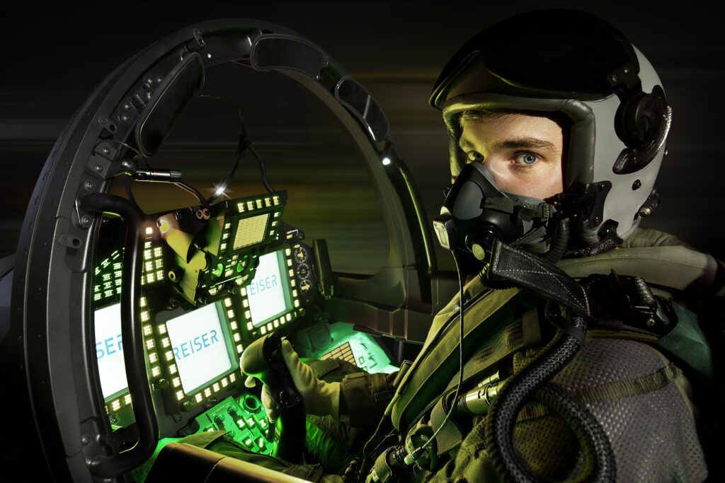 Person wearing a flight helmet in an illuminated Eurofighter cockpit